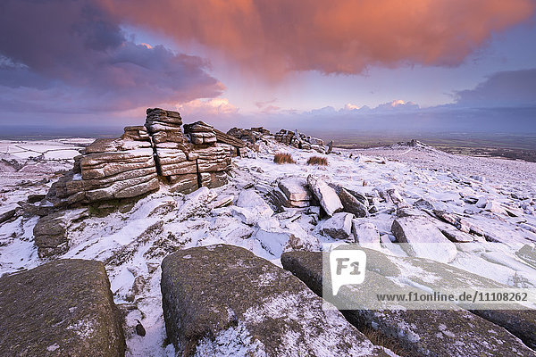 Colourful sunrise above snow covered moorland  Belstone Tor  Dartmoor  Devon  England  United Kingdom  Europe
