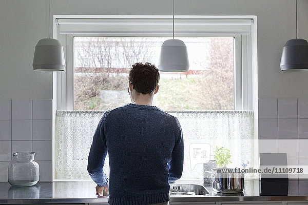 Rear view of man working in kitchen at home