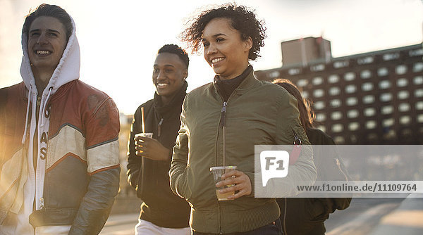 Lächelnde Teenagerfreunde mit Einwegbechern beim Spaziergang in der Stadt
