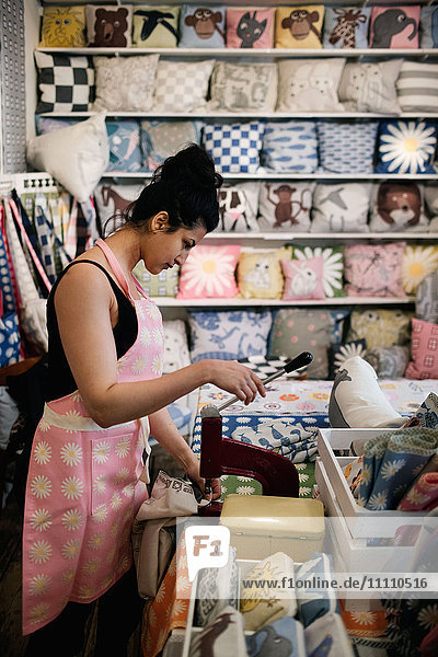 Seitenansicht der Frau beim Stanzen auf Textil während der Arbeit in der Werkstatt