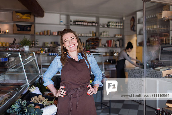 Portrait of smiling woman standing with hands on hip at store