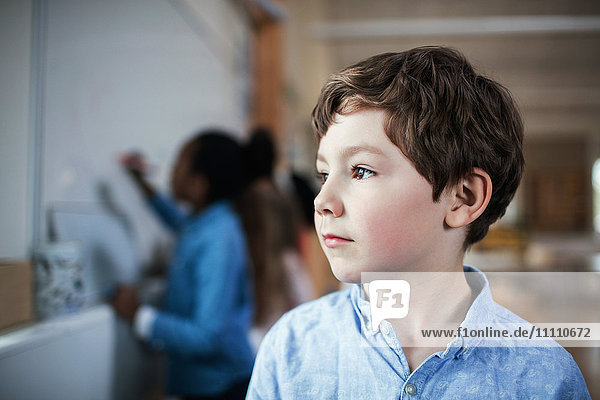 Close-up of male student looking away while standing in classroom