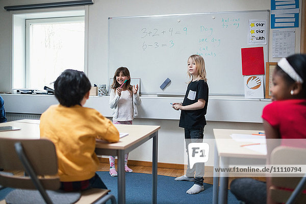 Students explaining to classmates in classroom