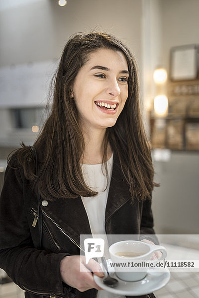 Lächelnde Frau mit einer Tasse Kaffee in der Hand