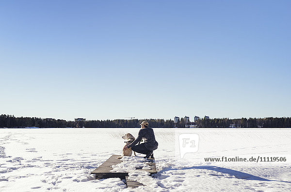 Schweden, Vasterbotten, Umea, Mann mit Hund mit Blick auf Winterlandschaft