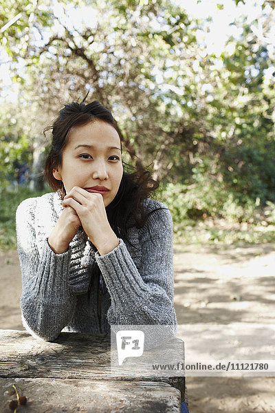 Asiatische Frau sitzt auf einer Picknickbank