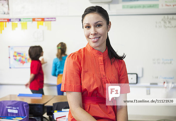 Gemischtrassiger Lehrer lächelt im Klassenzimmer