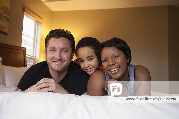 Smiling family laying on bed