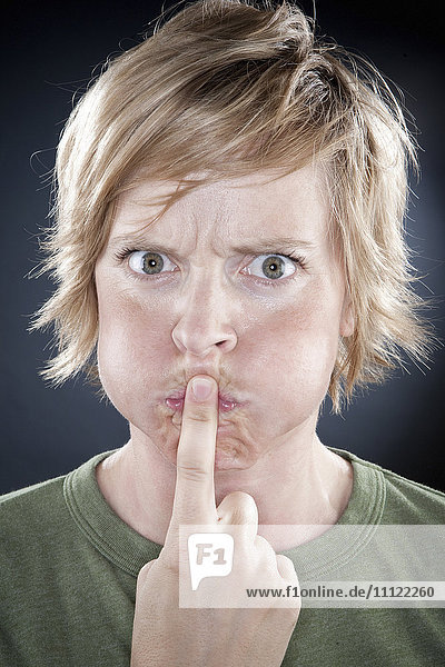 Caucasian woman holding finger over her mouth