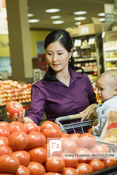 Mutter beim Einkaufen im Lebensmittelgeschäft mit Baby