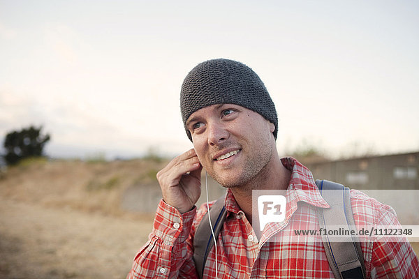 Man putting in earbuds in remote area