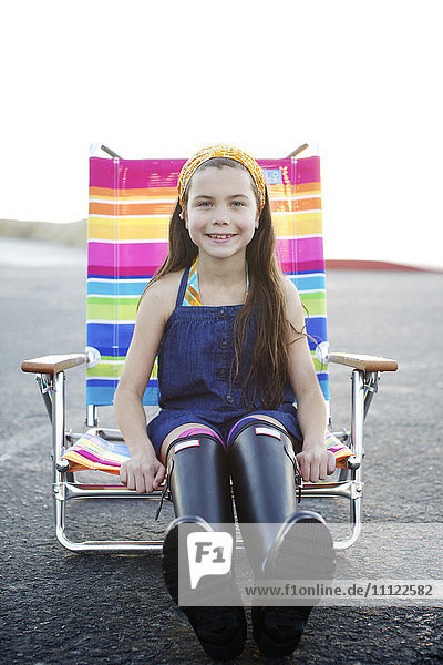 Mixed race girl sitting in lounge chair