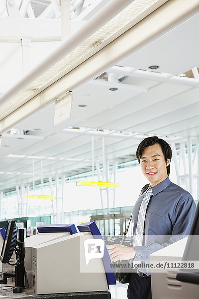 Asiatischer Geschäftsmann beim Einchecken am Flughafen