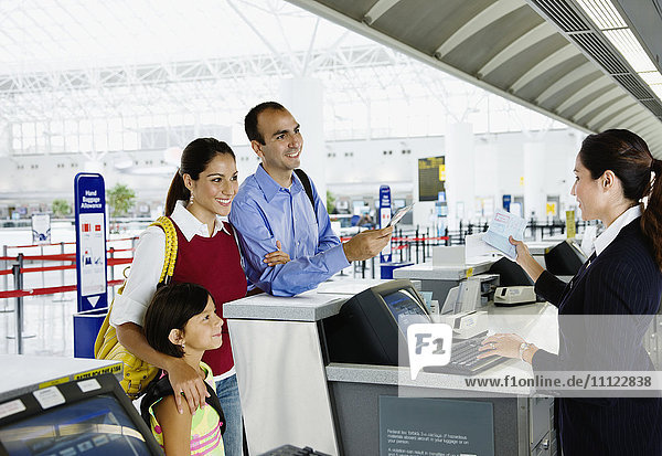 Hispanische Familie beim Einchecken am Flughafen