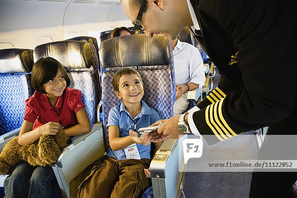 Flight attendant helping children on airplane