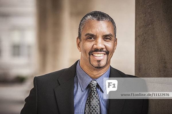 Mixed race businessman leaning on column