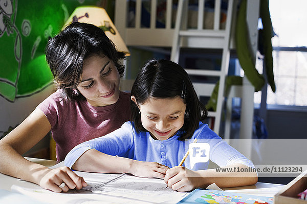 Hispanic mother helping daughter with homework