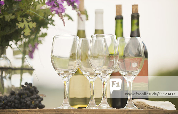 Weinflasche  Weintrauben und Gläser auf einem Tisch im Freien