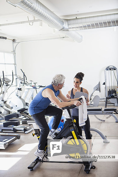 Älterer hispanischer Mann arbeitet mit Trainer im Fitnessstudio