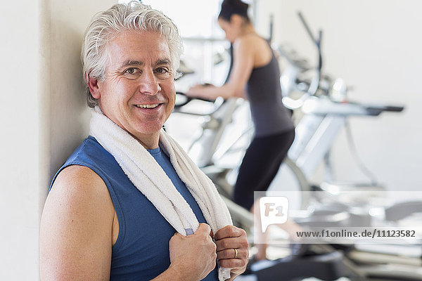 Older Hispanic man smiling in gym