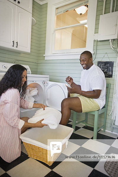 Afrikanischer Ehemann hilft seiner Frau beim Zusammenlegen der Wäsche