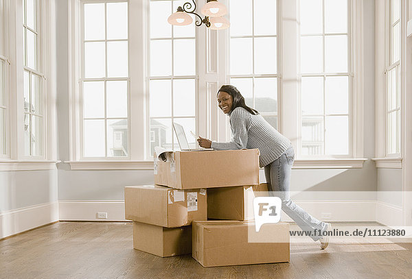 African woman using laptop on boxes