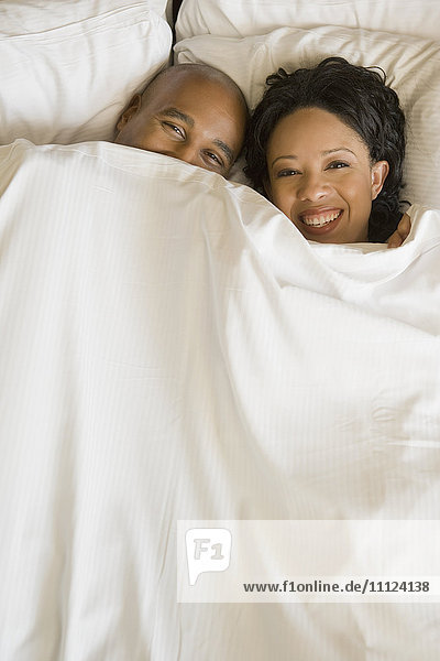 African couple in bed under blanket