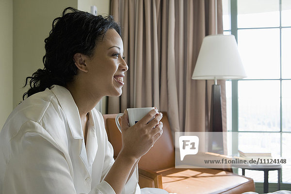 Afrikanische Frau trinkt Kaffee im Schlafzimmer