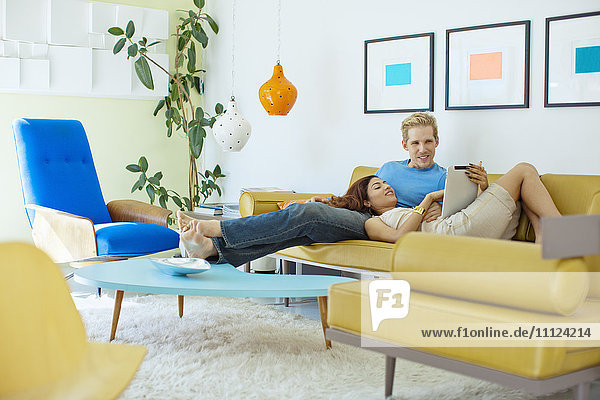 Glückliches Paar entspannt auf Sofa mit digitalem Tablet