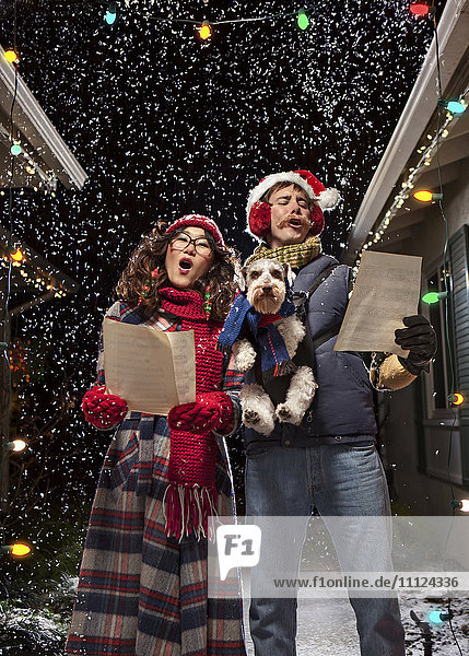 Ehepaar singt Weihnachtslieder mit Hund