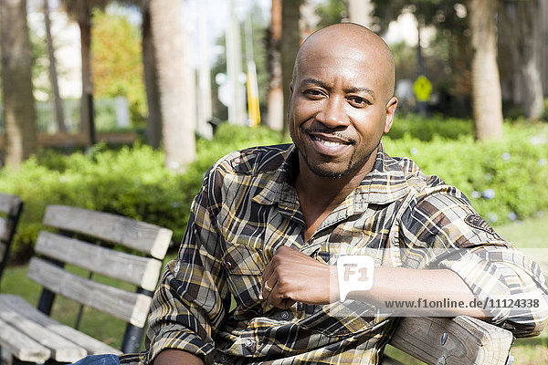 Black man smiling on park bench