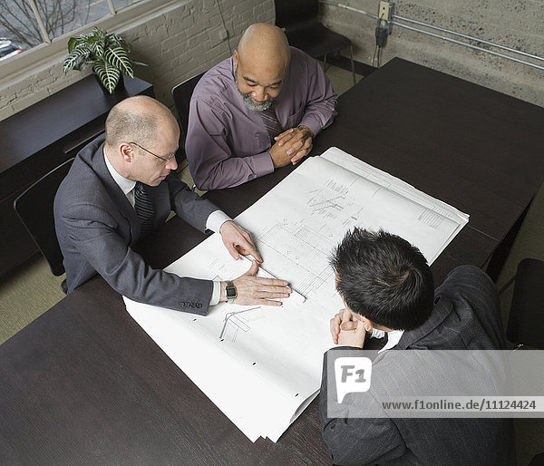 Geschäftsleute  die in einer Sitzung Baupläne prüfen