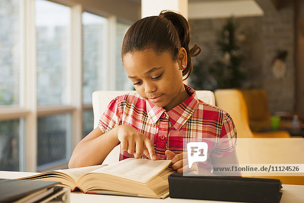 Afroamerikanisches Mädchen liest am Tisch