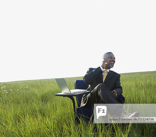Afrikanischer Geschäftsmann  der auf einem Feld mit seinem Handy telefoniert