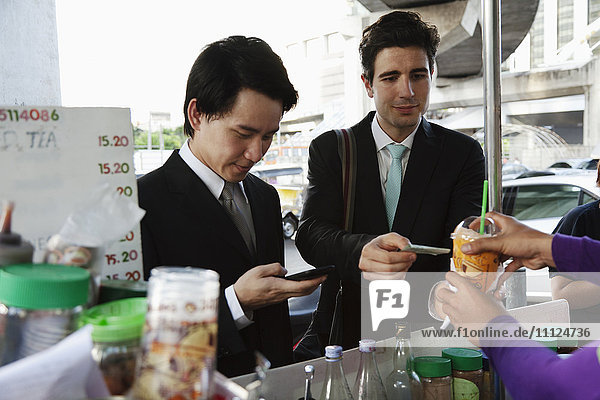 Businessmen buying lunch together at food cart