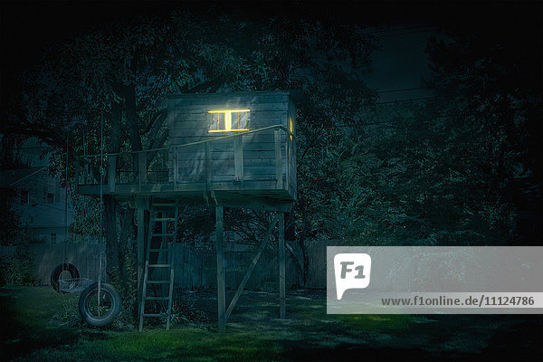 Beleuchtetes Baumhaus im Hinterhof bei Nacht