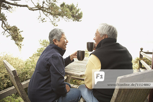 Älteres asiatisches Paar trinkt Kaffee im Freien