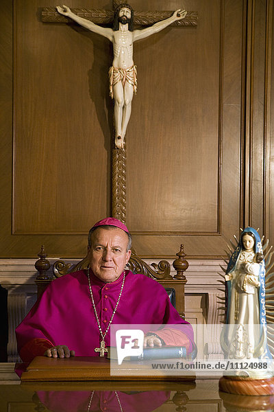 Hispanischer Bischof mit Bibel sitzend
