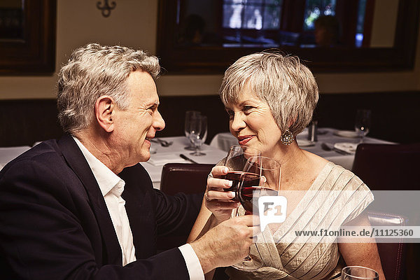 Ehepaar stößt mit Rotwein im Restaurant an