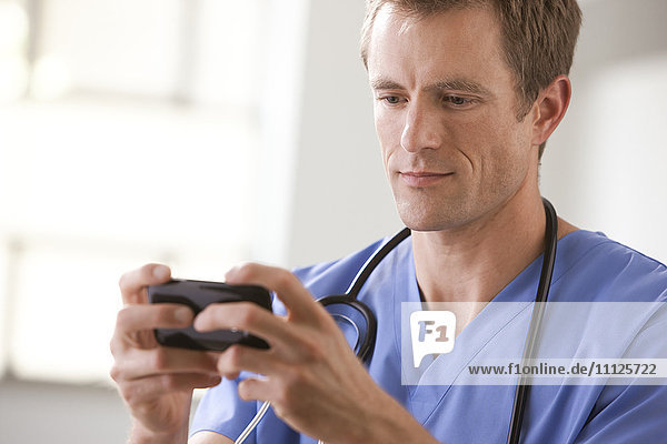 Caucasian surgeon text messaging on cell phone