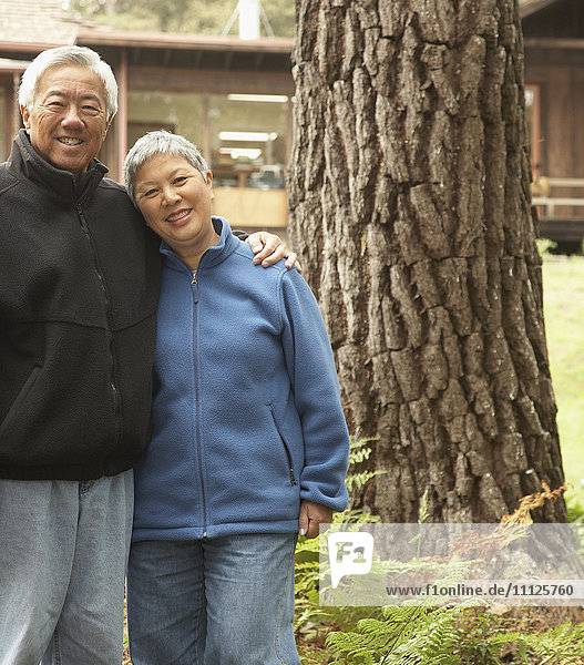 Älteres asiatisches Paar umarmt und lächelt im Freien