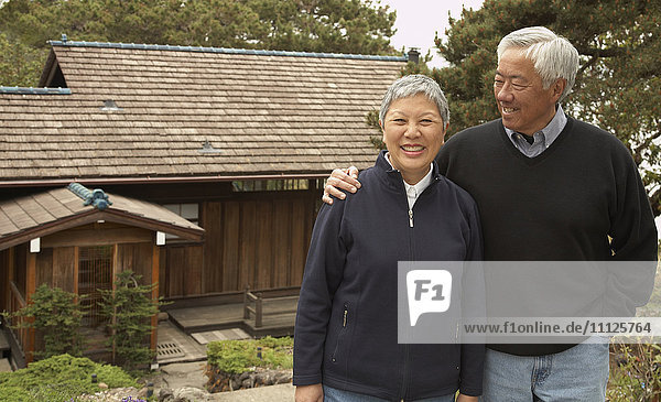 Älteres asiatisches Paar lächelnd und umarmend im Freien