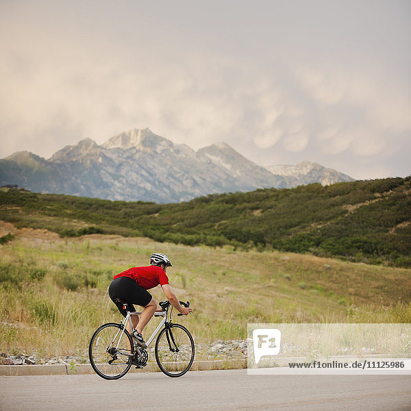 Caucasian man riding bicycle on remote road