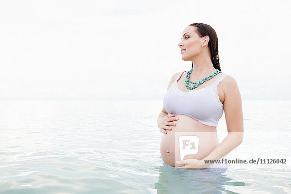 Schwangere kaukasische Frau im Wasser stehend