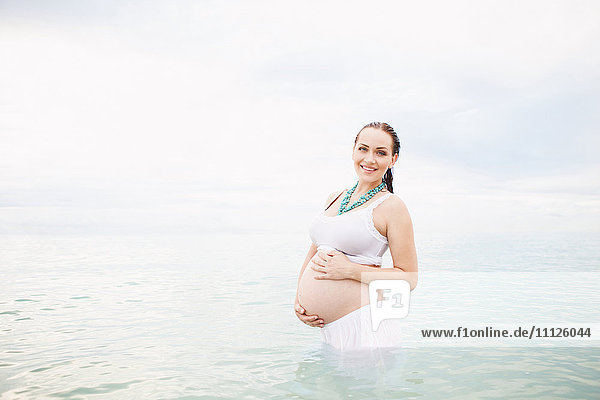 Schwangere kaukasische Frau im Wasser stehend