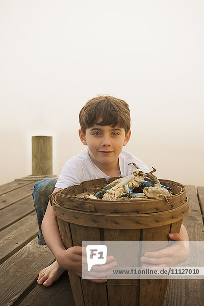 Kaukasischer Junge hält Korb mit Krabben