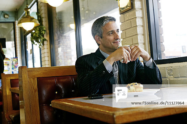 Hispanic businessman having coffee in restaurant