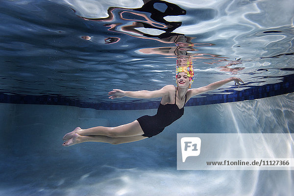 Gemischtrassige Frau schwimmt unter Wasser