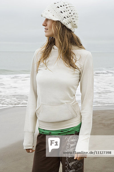 Gemischtrassige Frau mit Hut am Strand