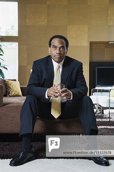 Confident African businessman sitting in modern living room